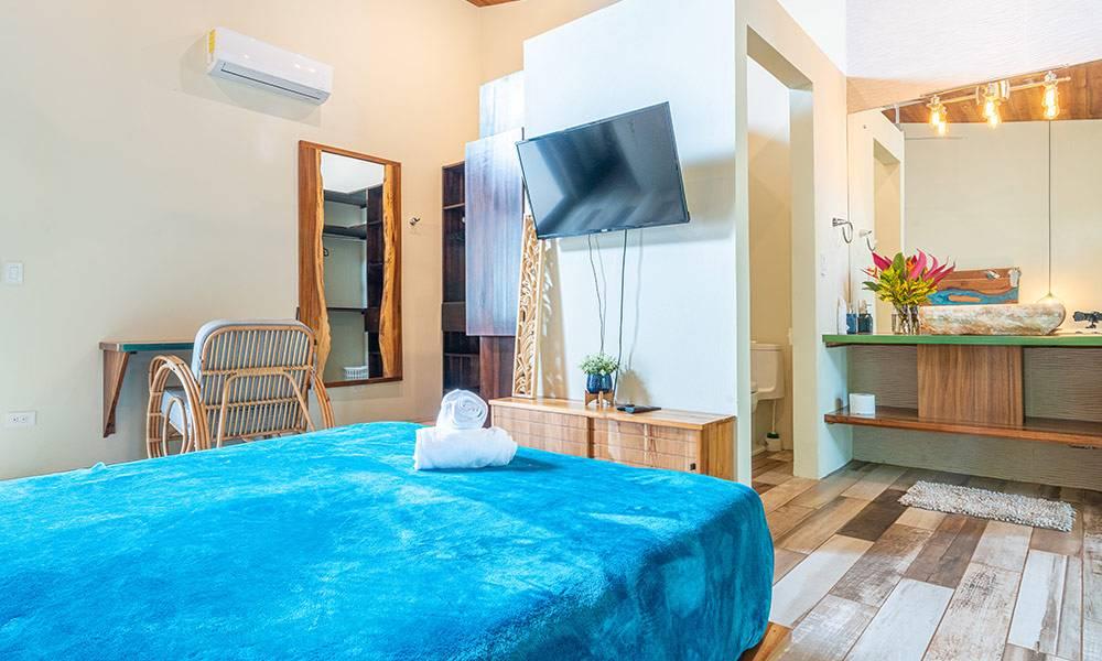 This bright bedroom features vaulted ceilings, natural wood accents, and an integrated en-suite bathroom with a distinctive stone basin.