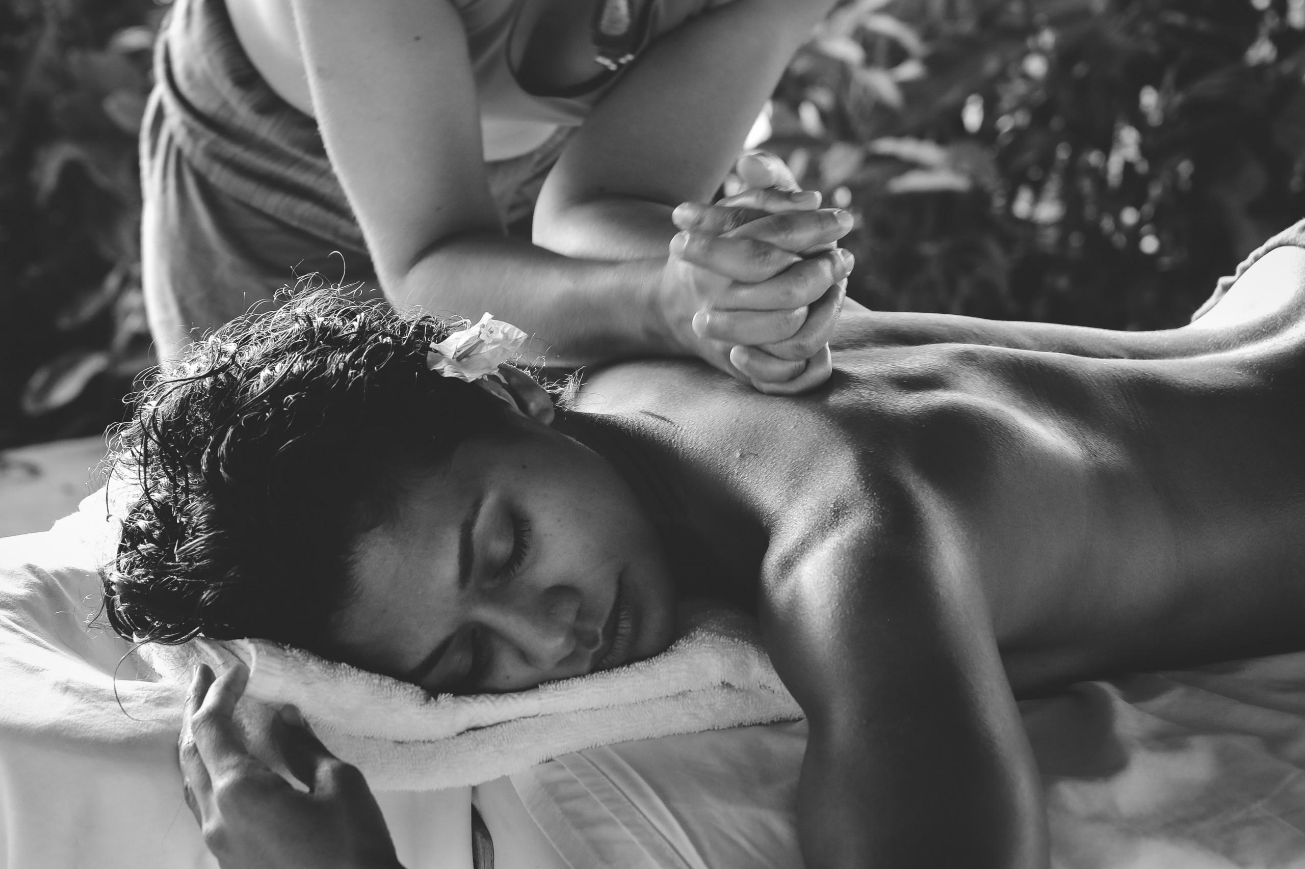 An outdoor area bathed in natural light provides a peaceful setting for a relaxing massage surrounded by tropical foliage.