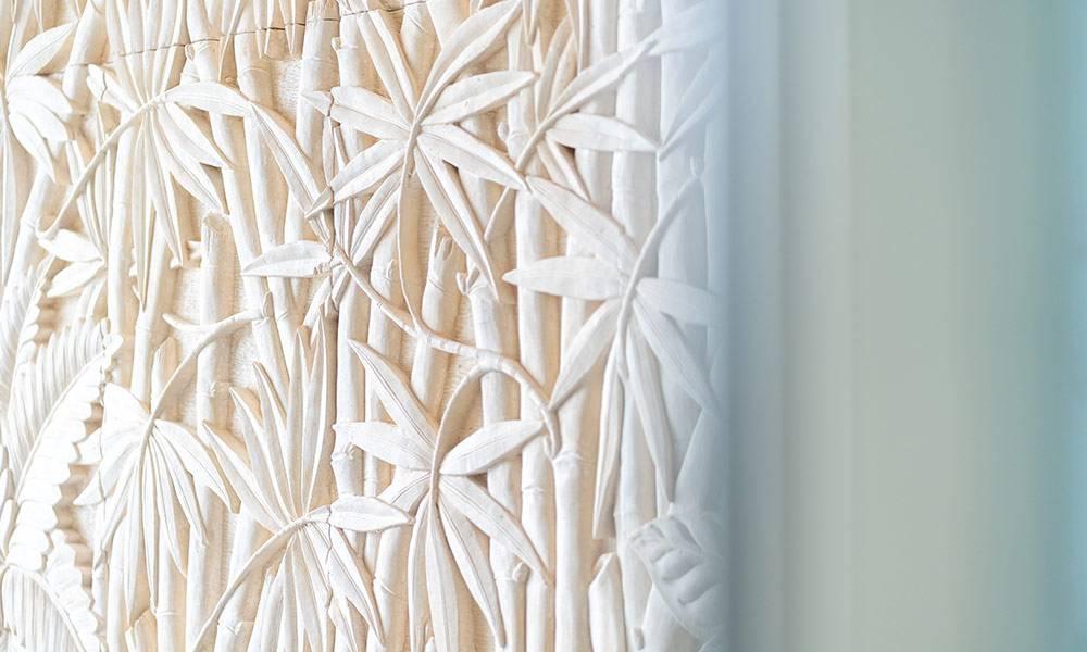 The interior space features a carved relief panel depicting bamboo and tropical foliage, naturally lit by light filtering from a nearby window.