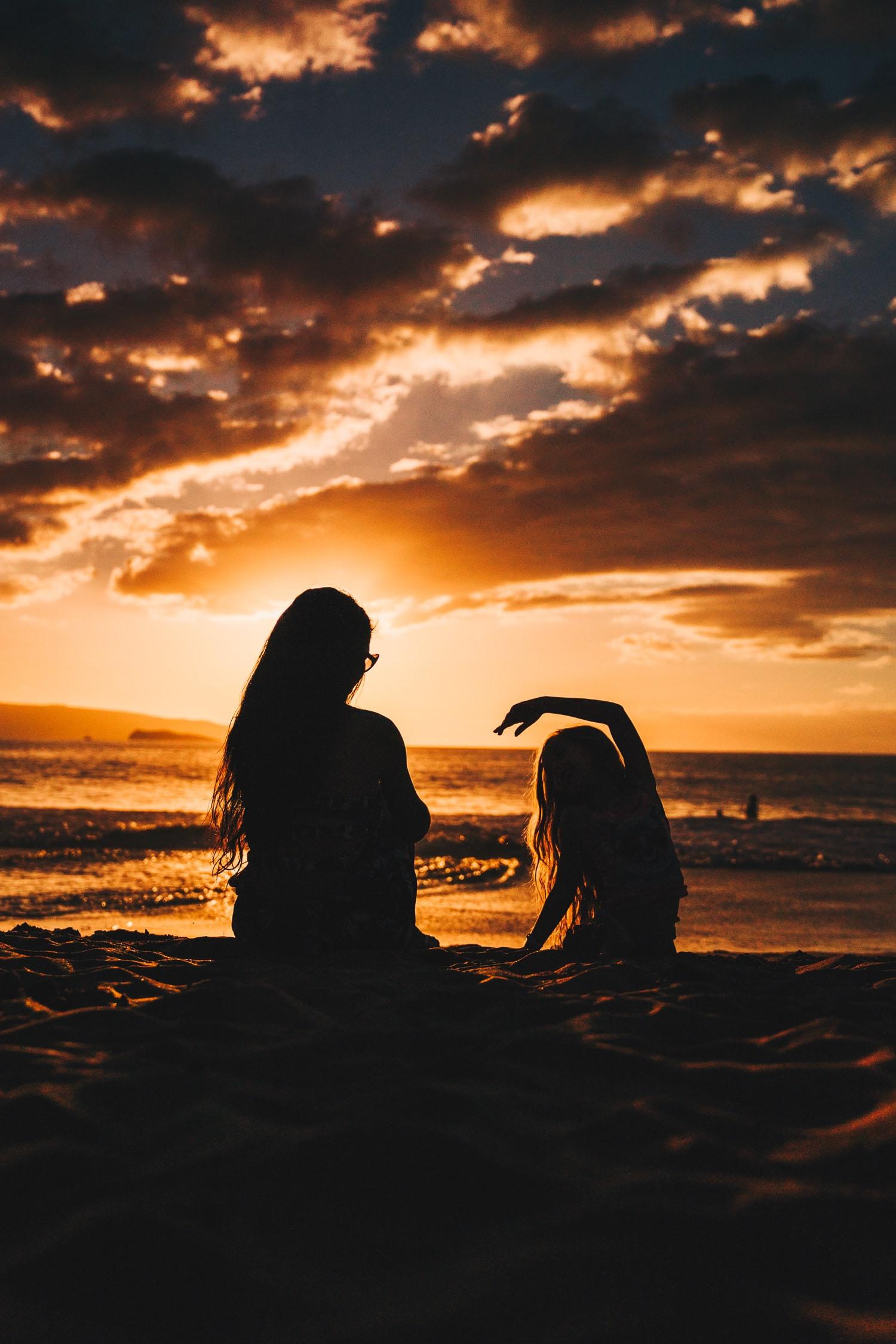 A golden sunset illuminates the sky and ocean from a sandy beach, offering a tranquil coastal experience.
