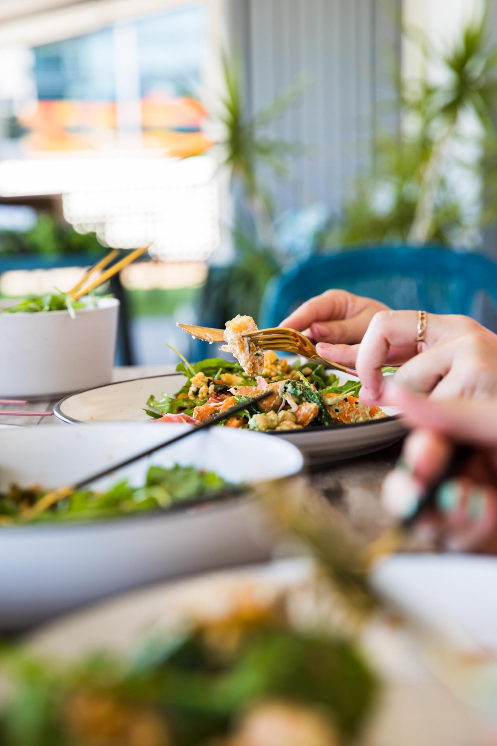 A bright outdoor dining area on the covered porch, featuring natural light and surrounding tropical plants.