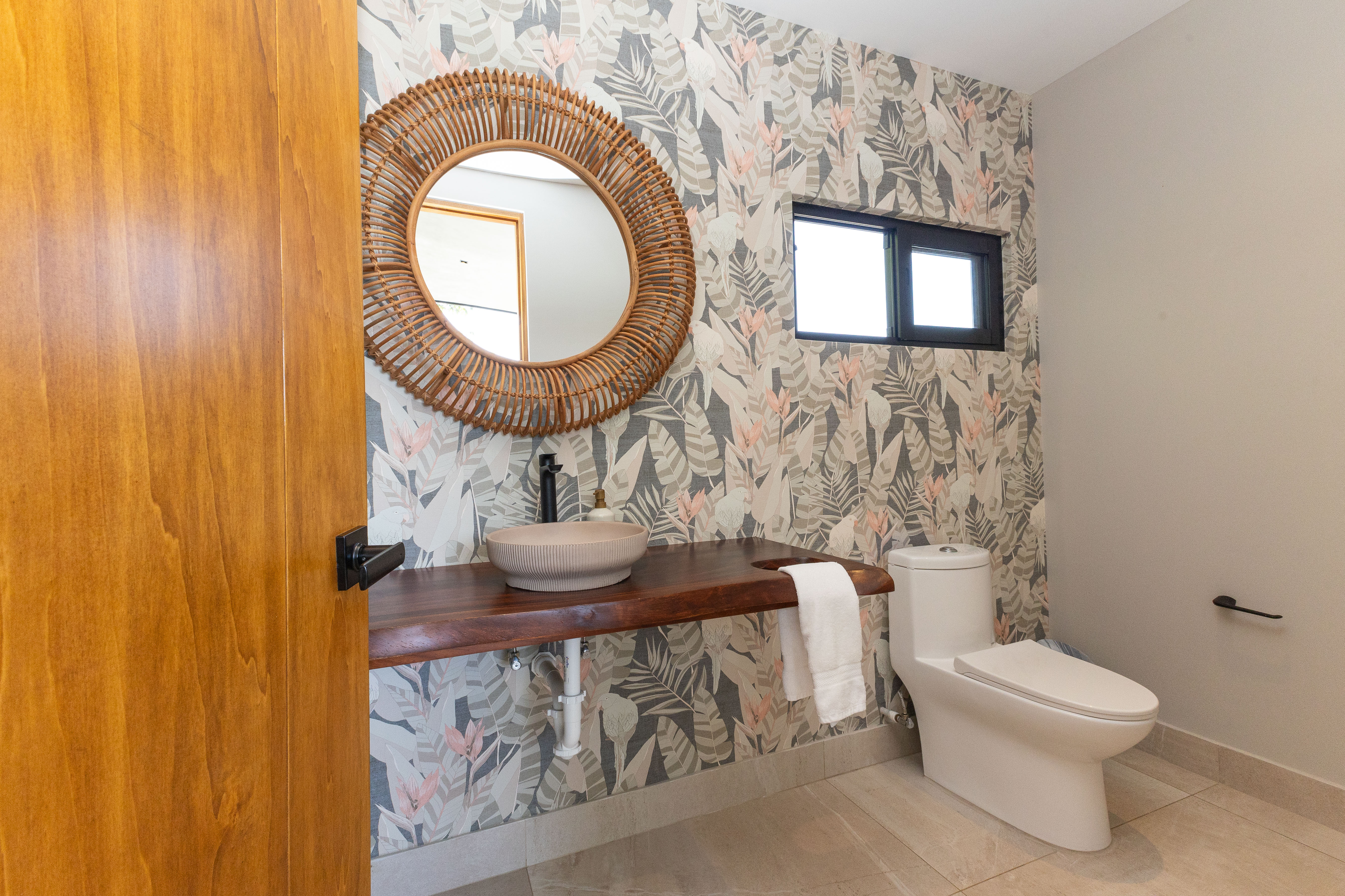 The bathroom features a jungle-themed accent wall, a live-edge wooden vanity with a modern basin sink, and a window bringing in natural light.