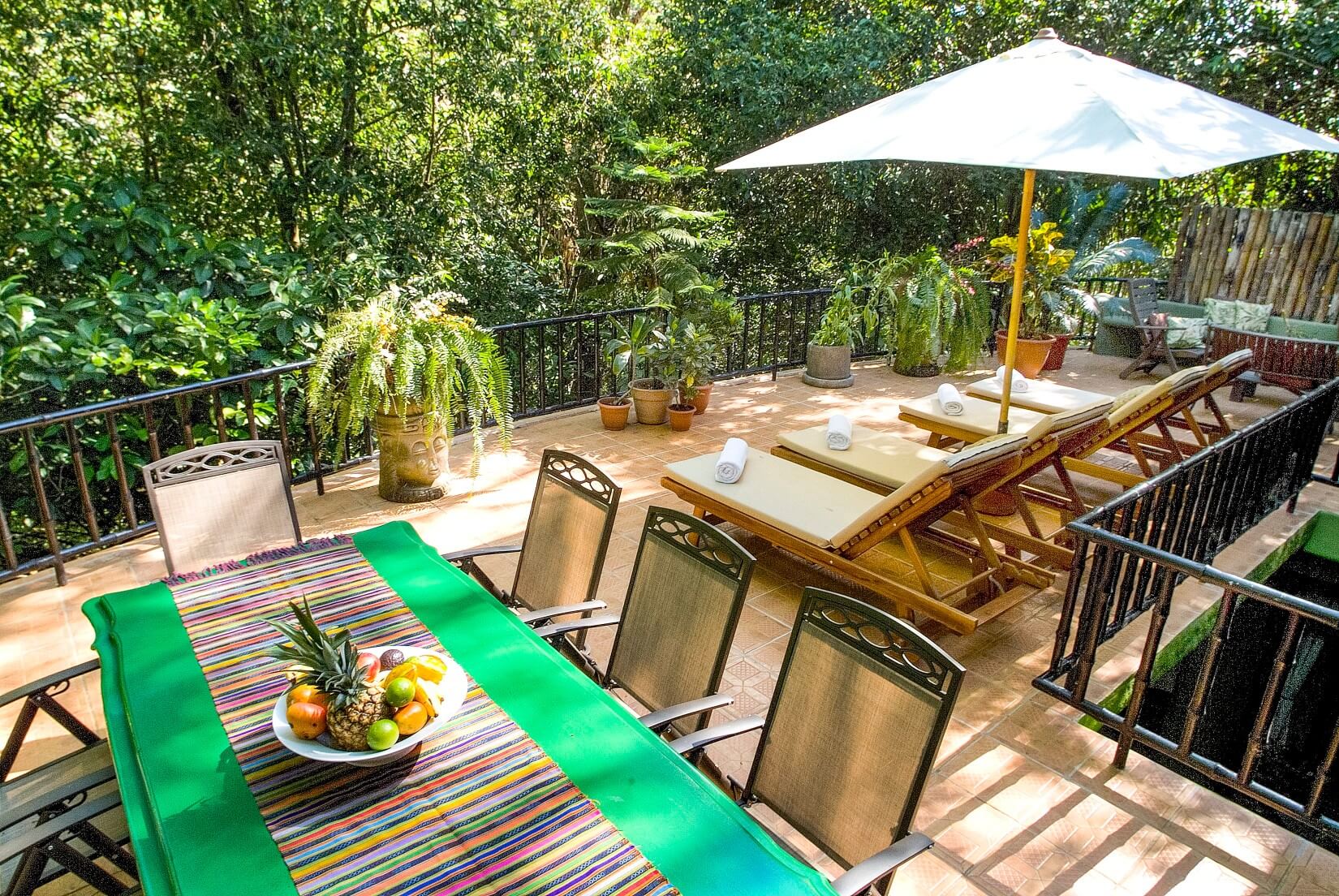 This bright outdoor terrace provides shaded and sunny lounging alongside a dining area, immersed in lush jungle views.