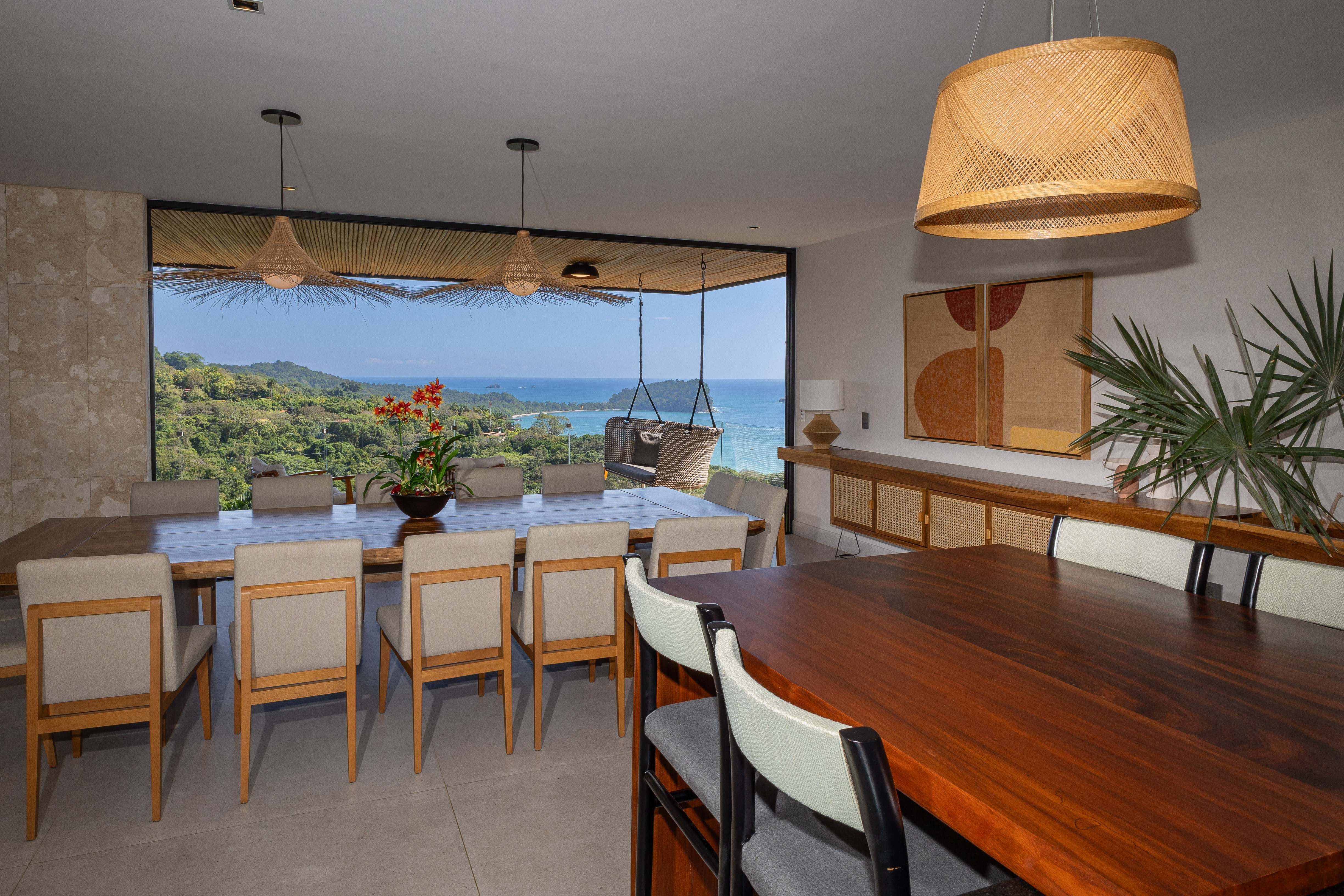 This bright, open dining space features floor-to-ceiling glass walls that frame panoramic views of the Pacific Ocean and lush jungle.