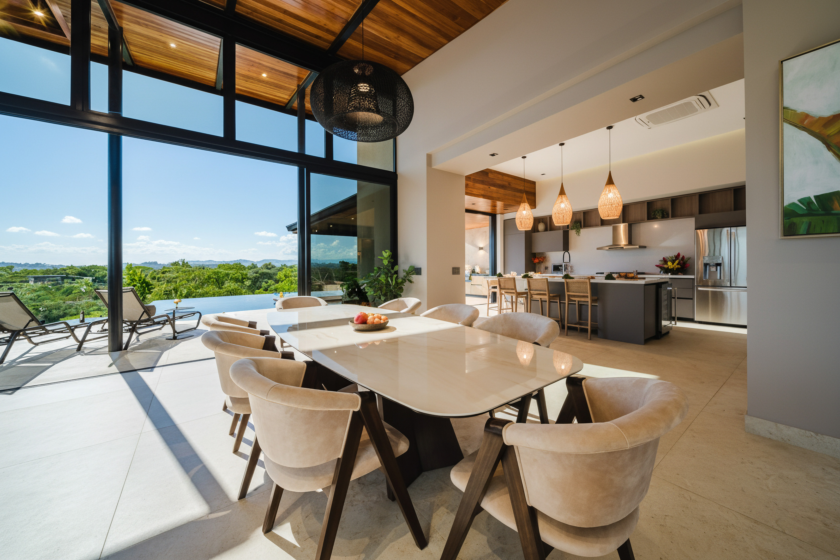 The bright dining area, featuring a large table and seating for eight under a wood-paneled ceiling, opens through expansive glass walls to a tropical landscape view and an outdoor pool, seamlessly connecting to a modern kitchen with island seating.