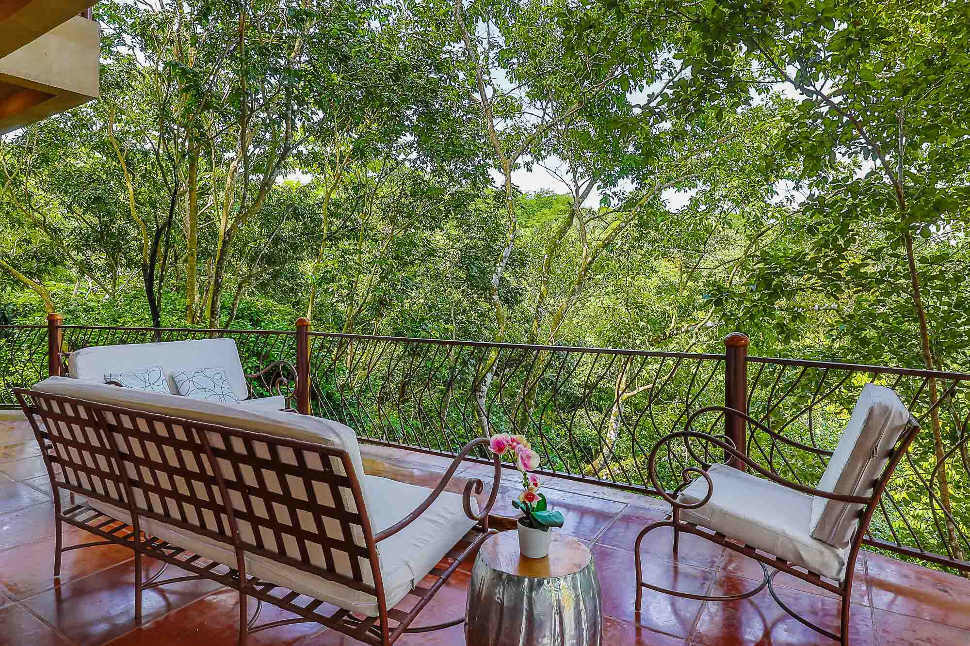 A private terrace features comfortable outdoor seating and expansive views into the surrounding Costa Rican rainforest.