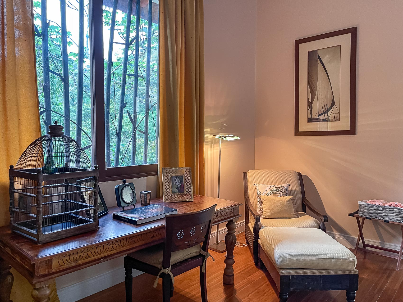 This private space provides a comfortable wooden desk and chaise lounge, illuminated by natural light from a large window overlooking a lush tropical landscape.