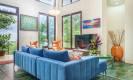 The spacious living area features high ceilings and extensive glass walls that invite natural light and frame vibrant jungle views.