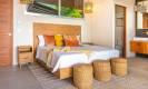 A bright, spacious king bedroom with warm wood furnishings and an en-suite bathroom provides a comfortable space that opens to ocean views.